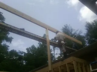 Carpenter setting a ridge beam over a new addition frame — Ice Dam Removal by Roofing Brothers in Albany