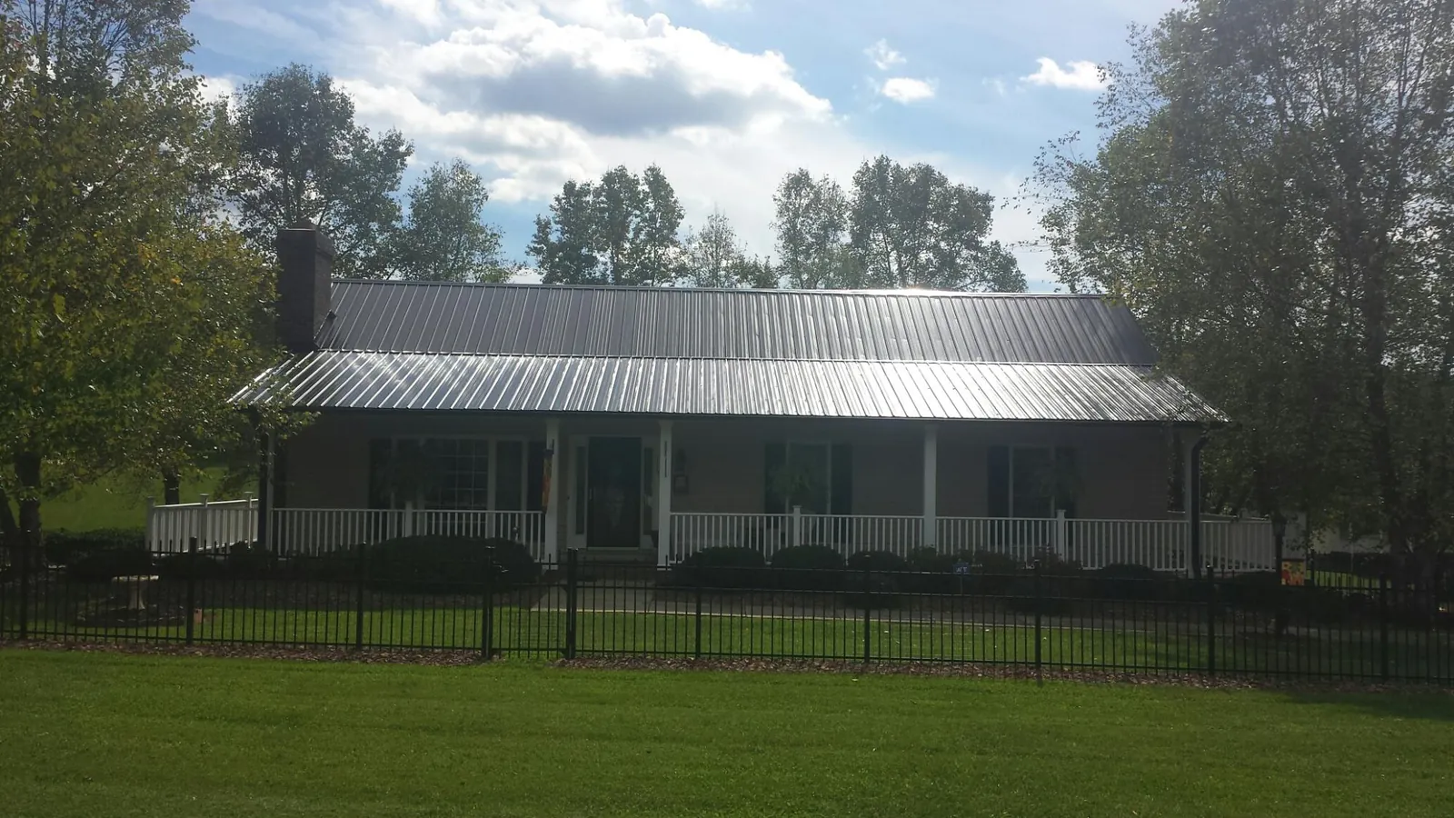 Gray metal roof on a brick ranch with a full width front porch — Gutter Guard Installation work by our crew in Albany